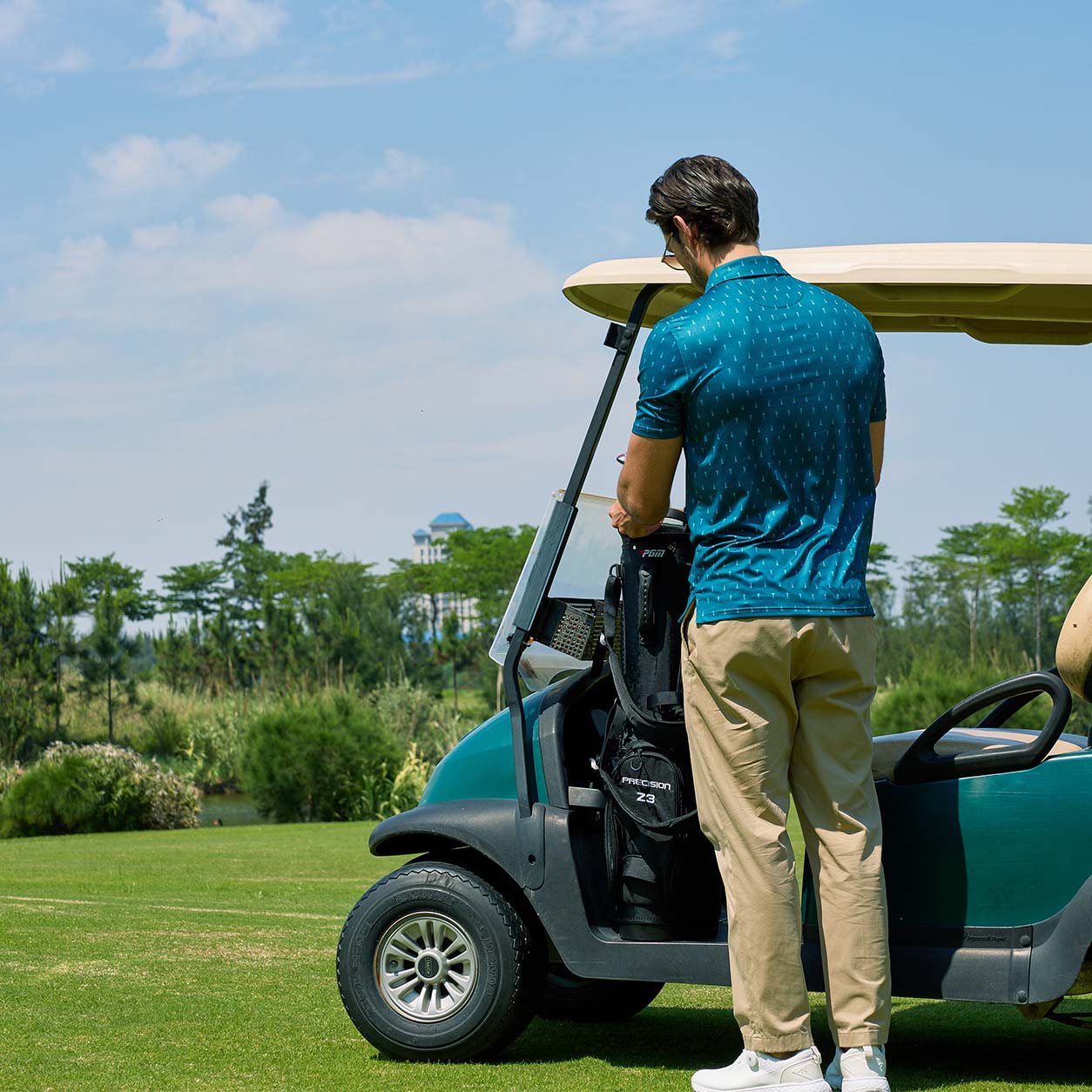 There is a man wearing a printed polo shirt on the golf course